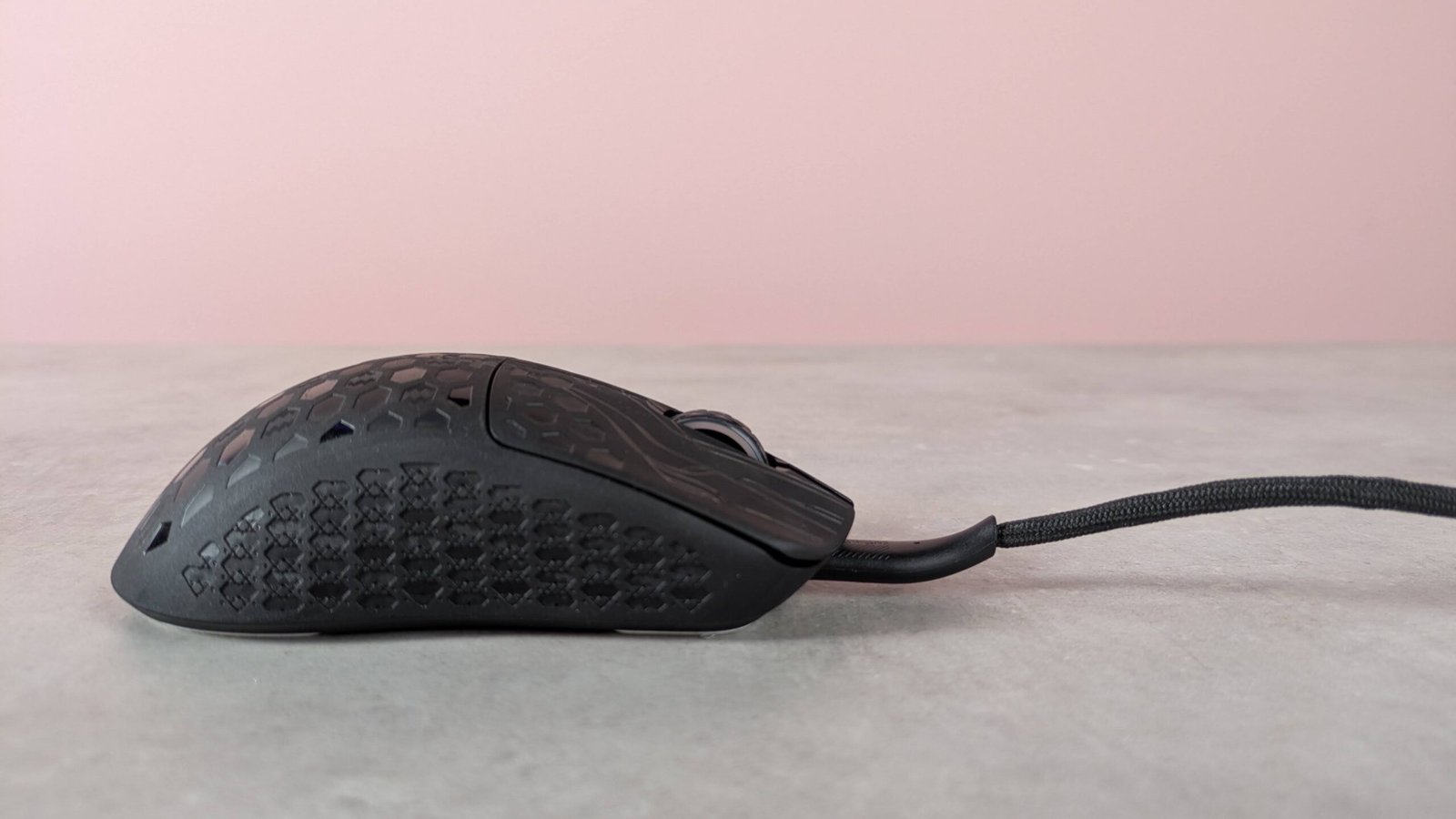 Side view of Keychron G5  with cable attached, on a desk with pink wall in background
